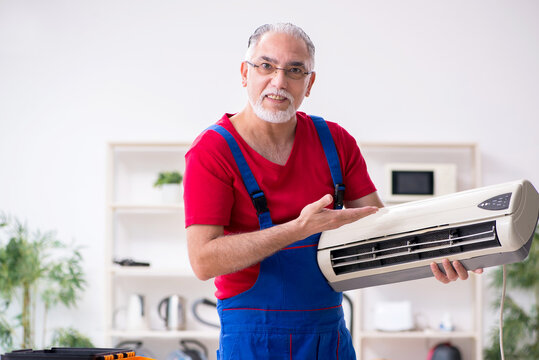 Old Male Contractor Repairing Air-conditioner Indoors