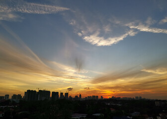 Warm sunset over city landscape with tall buildings and sky scrapers' silhouette in the foreground