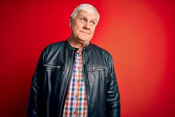 Senior handsome hoary man wearing casual shirt and jacket over isolated red background smiling looking to the side and staring away thinking.