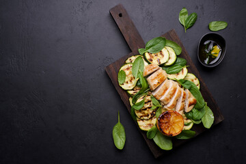 Grilled chicken breast with zucchini and spinach. Roasted chicken fillet with vegetable salad. Healthy food on white wooden table
