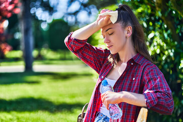 Young unhappy tired woman with cold refreshing water suffering from hot weather while walking in a...