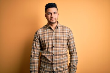 Young handsome man wearing casual shirt standing over isolated yellow background looking sleepy and tired, exhausted for fatigue and hangover, lazy eyes in the morning.