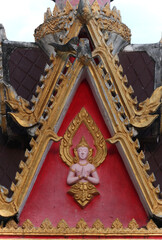 Fototapeta na wymiar Pediment design showing a buddha image on red background in a wat or buddhist temple in Siamese Lao PDR, Southeast Asia