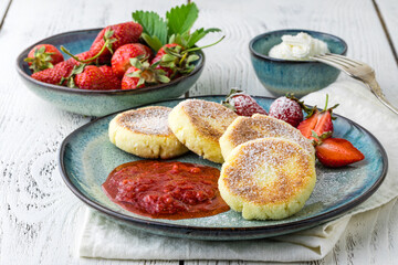Frying homemade Cottage cheese pancakes Russian syrniki with strawberry on  plate. Breakfast time