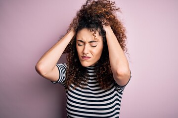 Young beautiful woman with curly hair and piercing wearing casual striped t-shirt suffering from...