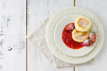 Frying homemade Cottage cheese pancakes Russian syrniki with strawberry on  plate. Breakfast time
