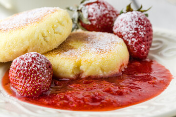 Frying homemade Cottage cheese pancakes Russian syrniki with strawberry on  plate. Breakfast time