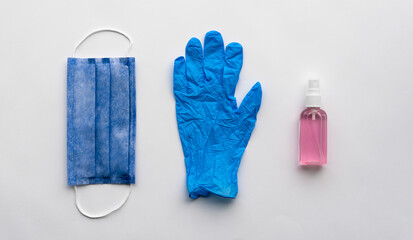 Protective kit against of  COVID-19. Close-up photo. Blue medical mask and glove with red alcohol sanitizer gel. Isolated on a white background