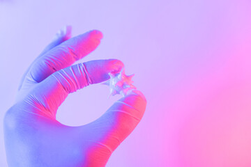 Doctor or scientist hold in hand in medical glove three-dimensional model of coronavirus. Concept photo of study or diagnosis of coronavirus infection. Neon duotone glowing color.
