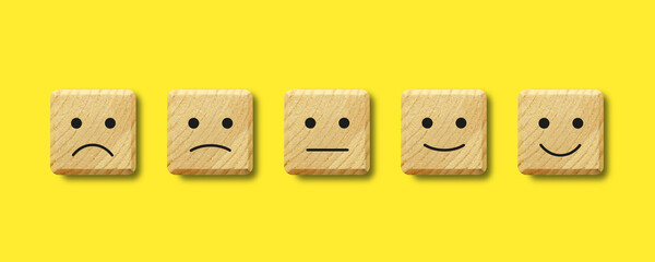 Five square wooden buttons with facial emotional expressions. Customer service evaluation and satisfaction ranking concepts. Feedback icons for client