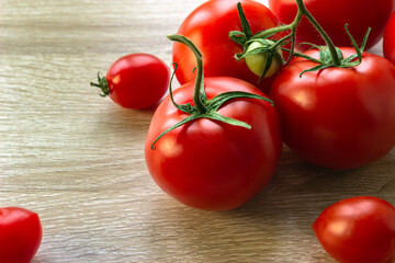 a handful of large tomatoes surrounded by a small, on a wooden table background