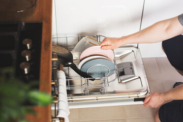 Man hands loading the dishwasher close up, man chores and hosework concept