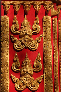 Golden painted buddha images on red background on a building of a temple site in Siamese Lao PDR, Southeast Asia