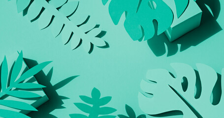 Toned photo of hand cut paper tropical plants leaves on the green background. Summer concept Top view
