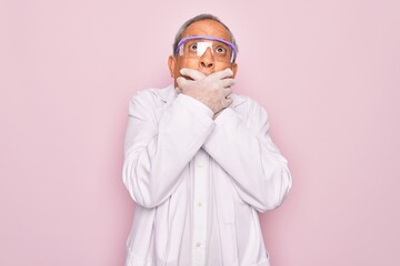 Senior grey-haired scientist man wearing glasses and coat over isolated pink background shocked covering mouth with hands for mistake. Secret concept.