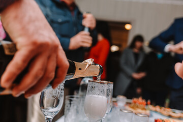 close-up hand pours champagne from a bottle into a glass of wine company