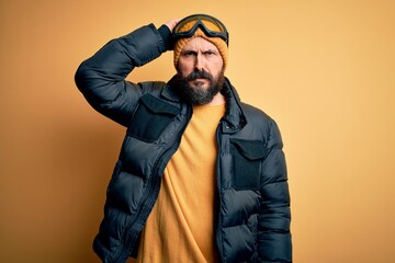 Handsome skier bald man with beard skiing wearing snow sportswear and ski goggles confuse and...