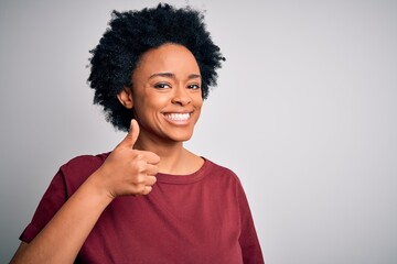 Young beautiful African American afro woman with curly hair wearing casual t-shirt standing doing...