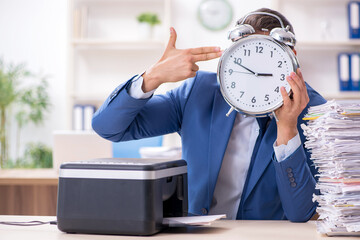 Young male employee making copies at copying machine