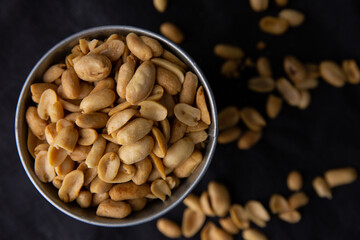A pile of peanuts in a zinc cup on a black top