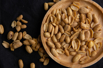A pile of peanuts in a wooden plate on the black top