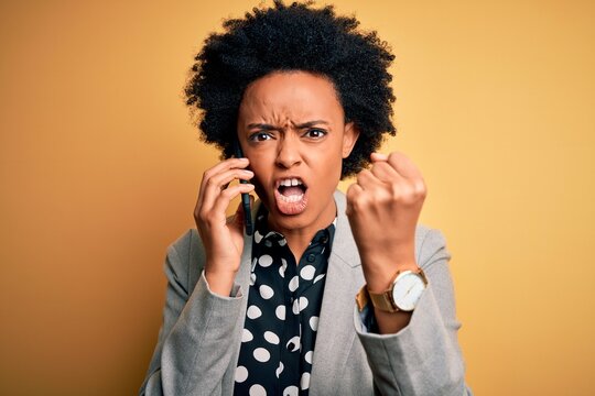 Young African American afro woman with curly hair having conversation talking on smartphone annoyed and frustrated shouting with anger, crazy and yelling with raised hand, anger concept
