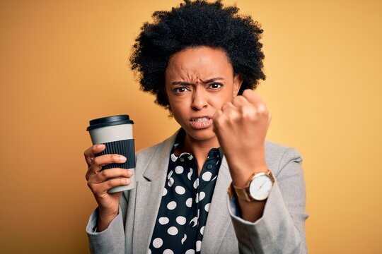 Young African American afro businesswoman with curly hair drinking cup of coffee annoyed and frustrated shouting with anger, crazy and yelling with raised hand, anger concept