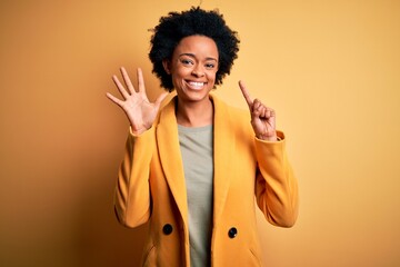 Young beautiful African American afro businesswoman with curly hair wearing yellow jacket showing and pointing up with fingers number six while smiling confident and happy.