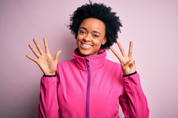 Young African American afro sportswoman with curly hair wearing sportswear doin sport showing and pointing up with fingers number eight while smiling confident and happy.