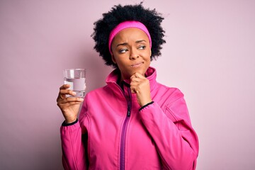 Young African American afro sportswoman with curly hair drinking glass of water serious face...