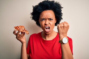 Young African American afro woman with curly hair eating slice of delicious Italian pizza annoyed and frustrated shouting with anger, crazy and yelling with raised hand, anger concept