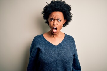 Fototapeta na wymiar Young beautiful African American afro woman with curly hair wearing casual sweater In shock face, looking skeptical and sarcastic, surprised with open mouth