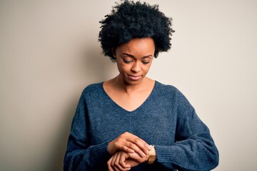 Young beautiful African American afro woman with curly hair wearing casual sweater Checking the...