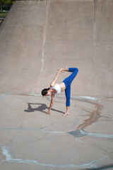 Asian chinese woman doing street yoga in public skate park