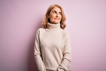 Obraz premium Middle age beautiful blonde woman wearing casual turtleneck sweater over pink background smiling looking to the side and staring away thinking.