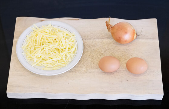 Onions cheese and eggs on wooden chopping board