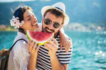 Young smiling couple eating watermelon on the beach having fun