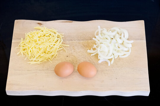Onions cheese and eggs on wooden chopping board