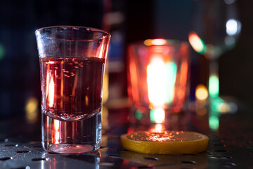 a glass of vodka with gin rum sambuca tequila and a slice of lemon on a bar in a nightclub