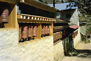 Buddhist prayer cylinders containing mantras, holy words, on Tibetan monastery in a village amid...