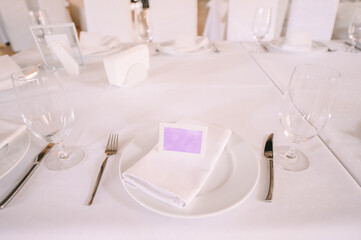 Presidium, banquet table with a white tablecloth. Plates and cutlery, glasses, napkins.