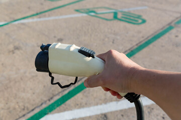 Hand holding Electric car charger. Electric Vehicle EV Charging station & Charger. Human hand is holding Electric Car Charging connect to Electric car.