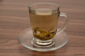 A cup of green tea and its leaves inside.