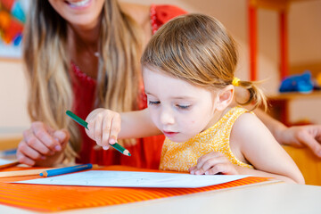Children drawing with pencils in play school