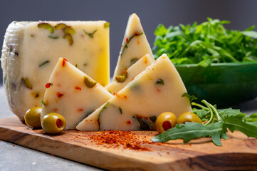 Cheese collection, fresh Italian pecorino cheese made from sheep milk filled with green olives stuffed with red paprika, green ruccola rocket salad and cayenne pepper