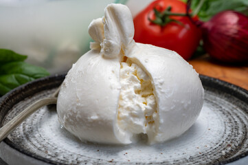 Eating of fresh handmade soft Italian cheese from Puglia, white balls of burrata or burratina...