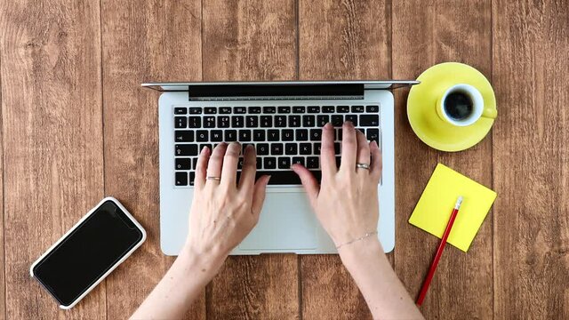 Computer laptop usage for creative remote home office work. Young woman using keyboard and smartphone for modern digital enabled corporation.