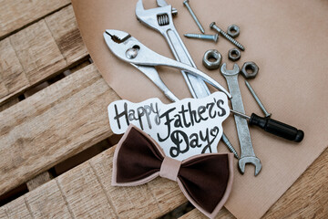 father's day background for congratulations, instruments in a mug on a wooden background with a bow tie, happy fathers day