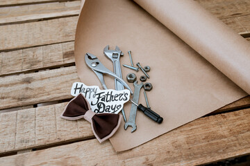father's day background for congratulations, instruments in a mug on a wooden background with a bow tie, happy fathers day