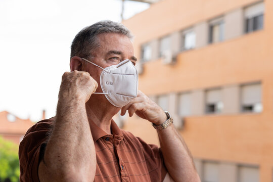 old Man removing mask at the balcony of house - Powered by Adobe